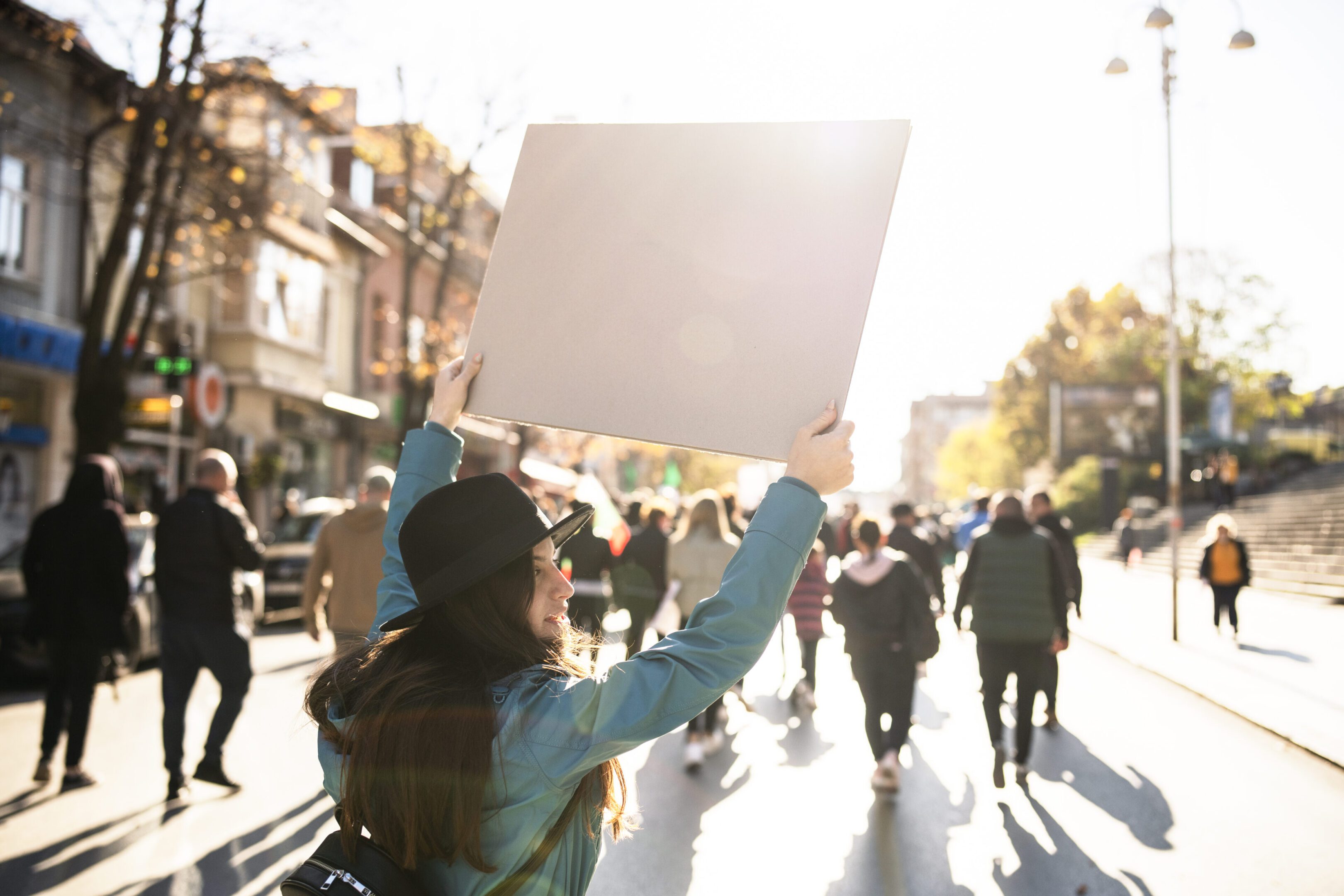 Person holding blank sign in sunny protest