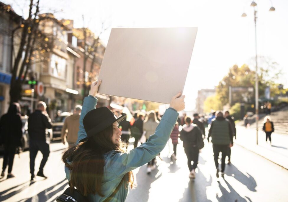 Person holding blank sign in sunny protest